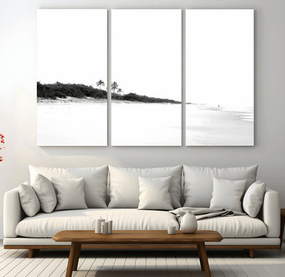 A black and white minimalist coastal scene with a vast open beach, distant palm trees, and a lone figure walking along the shoreline, evoking serenity and solitude.