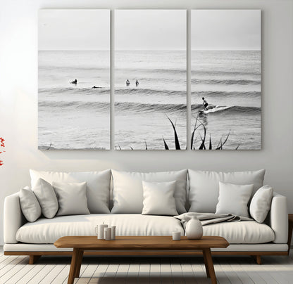 Monochrome canvas of surfers on calm ocean waves, ideal for minimalist coastal or beach-inspired interior decor.
