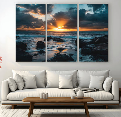 An awe-inspiring sunset over the ocean with rays of light piercing through dramatic clouds, creating a beautiful seascape with rocks in the foreground.
