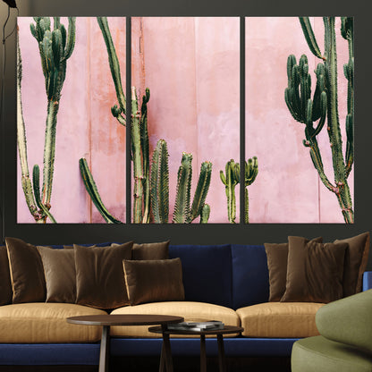 Framed canvas of tall green cacti against a soft pink wall, ideal for modern desert or colorful southwest-inspired home decor.