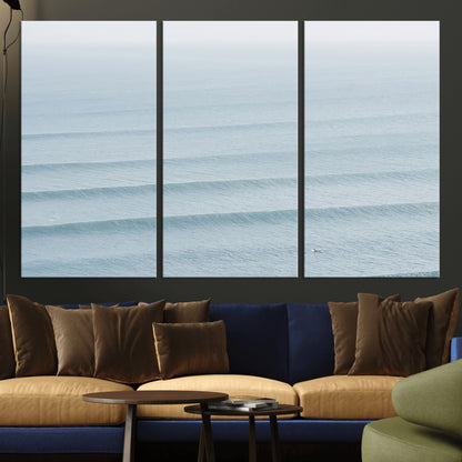 Framed canvas of repeating ocean waves with a distant solo surfer, ideal for minimalist ocean or calm coastal wall decor.