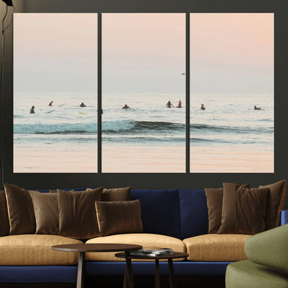 Dreamy photo of surfers waiting on soft pastel waves under a pink sunset sky, ideal for soft coastal minimalist or serene ocean-themed home decor.