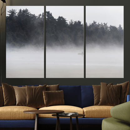 A lone surfer carrying a board through a misty shoreline, surrounded by dense trees and fog, creating a peaceful and mysterious coastal scene.