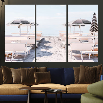 A serene minimalist beach scene featuring striped umbrellas, soft pastel sand, and an elegant lounge setup, creating a tranquil and stylish coastal retreat.
