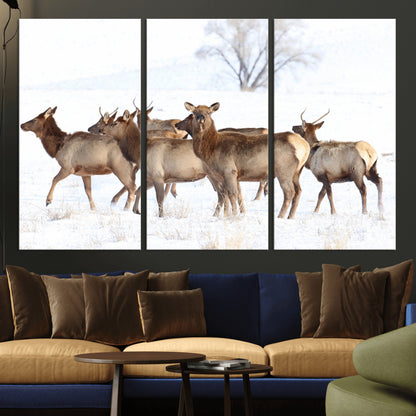 A group of elk standing on snowy terrain with a tree in the background, perfect for rustic or lodge-style winter wall decor.