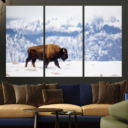 A lone bison walks across snowy ground with blue-toned mountain range behind, ideal for rustic or western farmhouse interiors.
