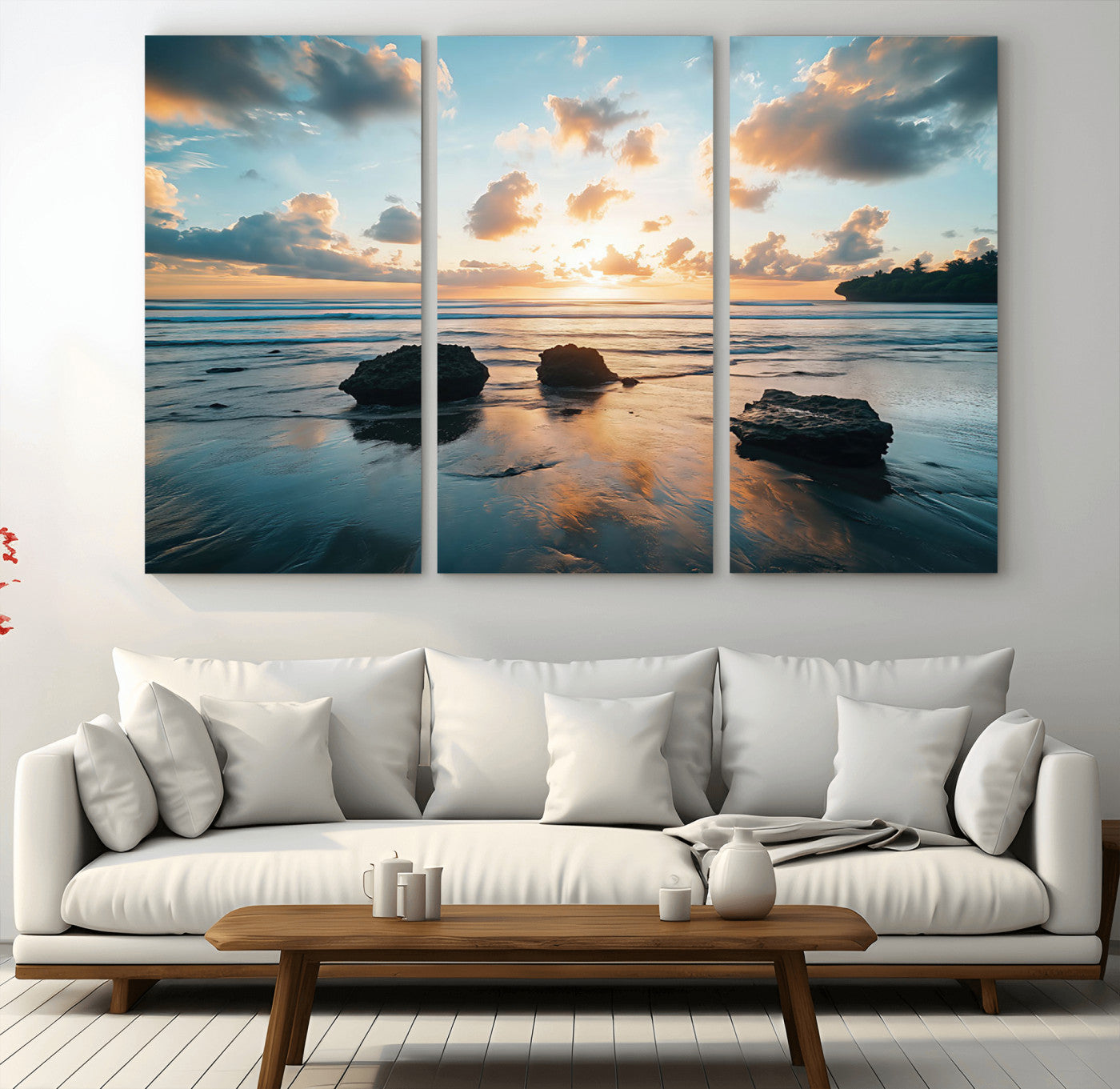 A serene beach at sunset with vibrant clouds, calm water, and rocks in the foreground reflecting the warm colors of the setting sun.