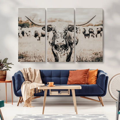 Canvas of a speckled Texas longhorn standing boldly in a field with a herd behind, perfect for rustic western or farmhouse wall decor.