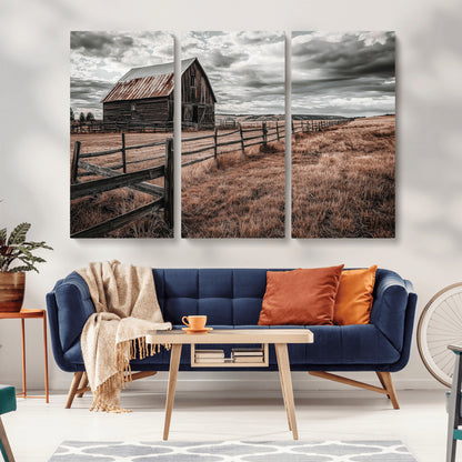 Framed canvas of a rustic barn under a moody sky with weathered fence and dark fields, ideal for farmhouse or rural-style wall decor.