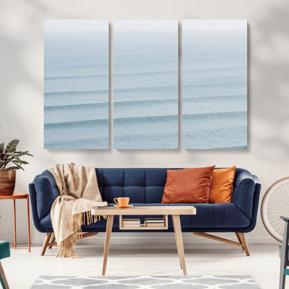 Framed canvas of repeating ocean waves with a distant solo surfer, ideal for minimalist ocean or calm coastal wall decor.