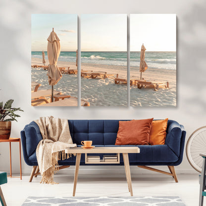 Minimalist photo of empty beach loungers and umbrellas on soft sand, ideal for calm seaside or pastel coastal-style home decor.