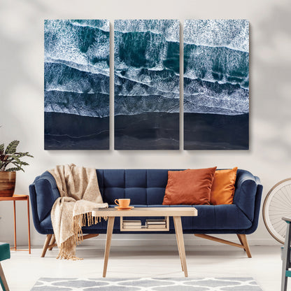 Canvas of aerial ocean waves crashing onto a black sand beach in moody tones, ideal for modern coastal or minimalist home decor.
