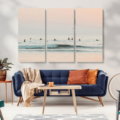 Dreamy photo of surfers waiting on soft pastel waves under a pink sunset sky, ideal for soft coastal minimalist or serene ocean-themed home decor.