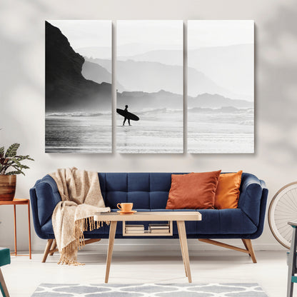 A lone surfer walking along a misty beach with cliffs in the background, carrying their board, capturing a serene and minimal ocean moment.