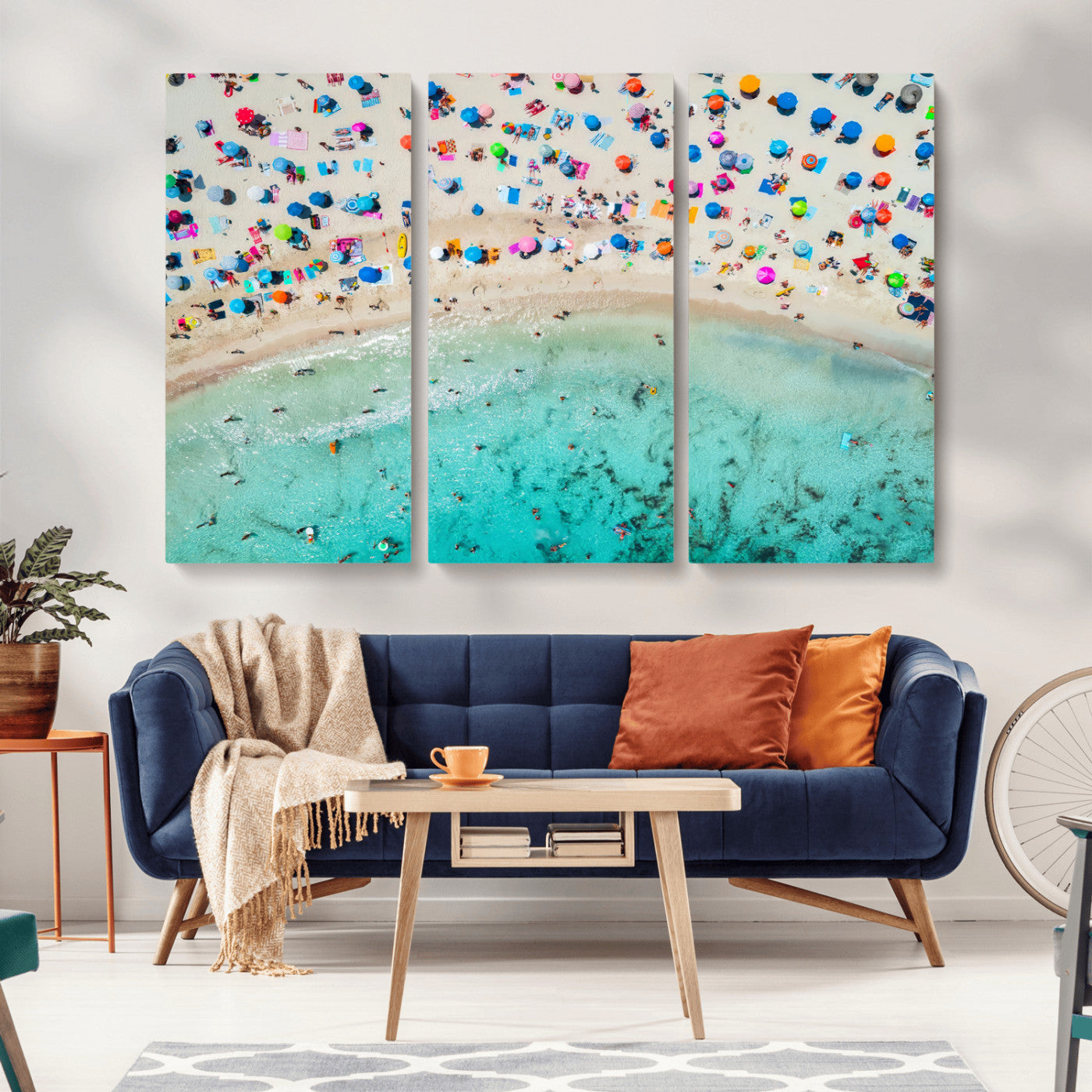 Aerial view of a vibrant beach filled with colorful umbrellas and people enjoying the turquoise ocean, capturing a lively summer vacation scene.