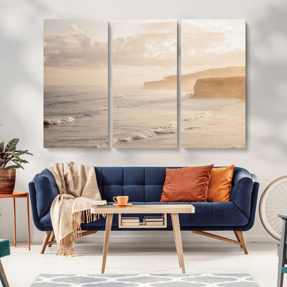 Golden hour seascape with misty cliffs and gentle waves rolling towards the shore, capturing a tranquil and warm coastal atmosphere.