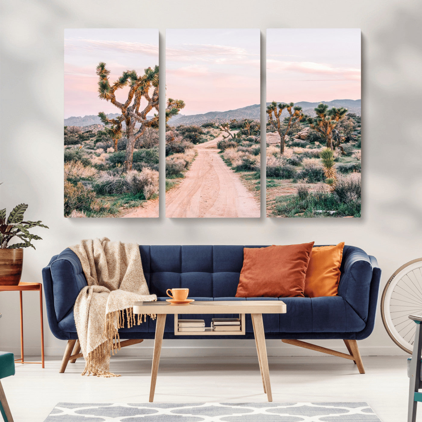 A dusty road winding through Joshua Tree National Park, framed by iconic twisted trees and warm desert tones under a soft pastel sky.