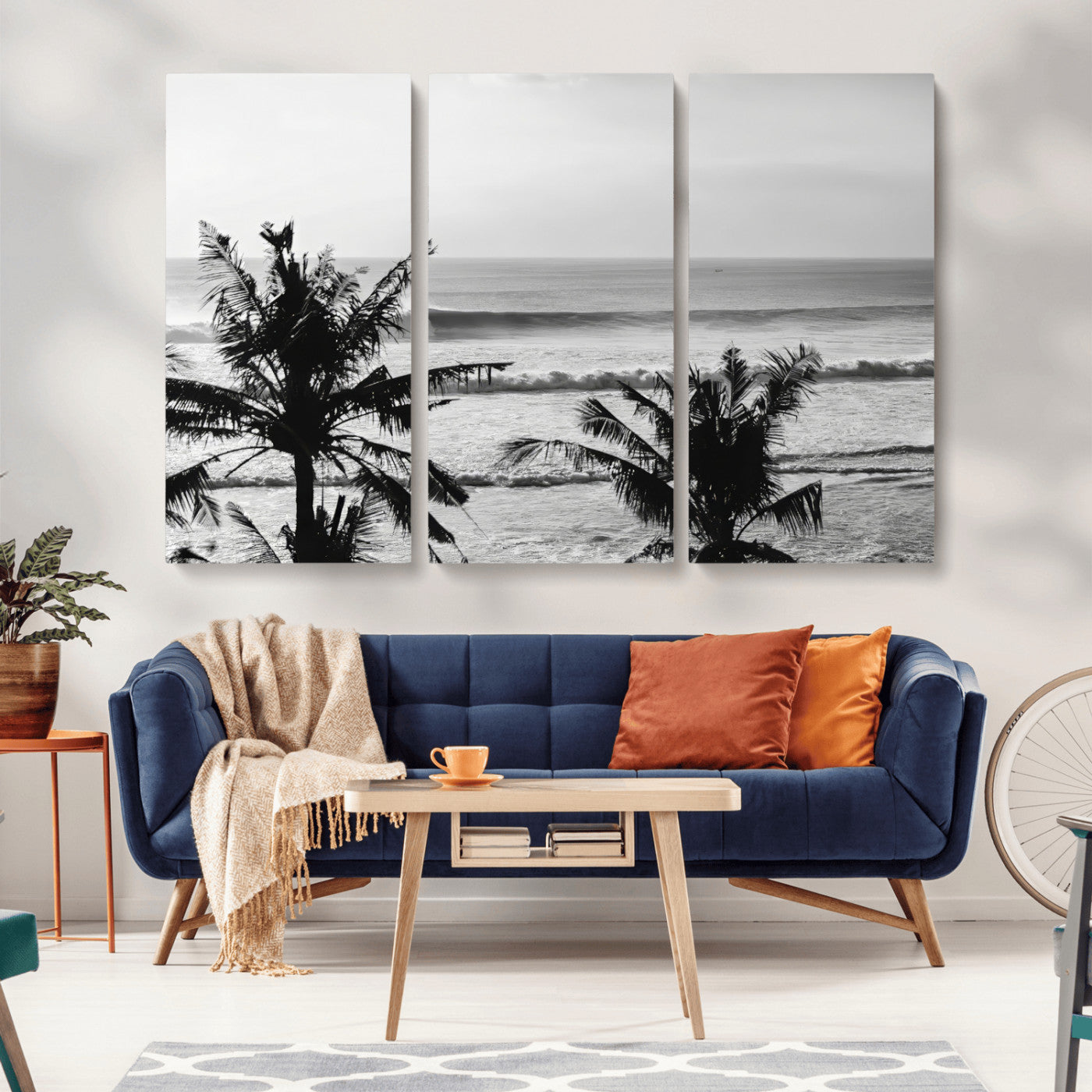 Black and white view of ocean waves crashing on a tropical coastline, framed by silhouetted palm trees under a vast, open sky.