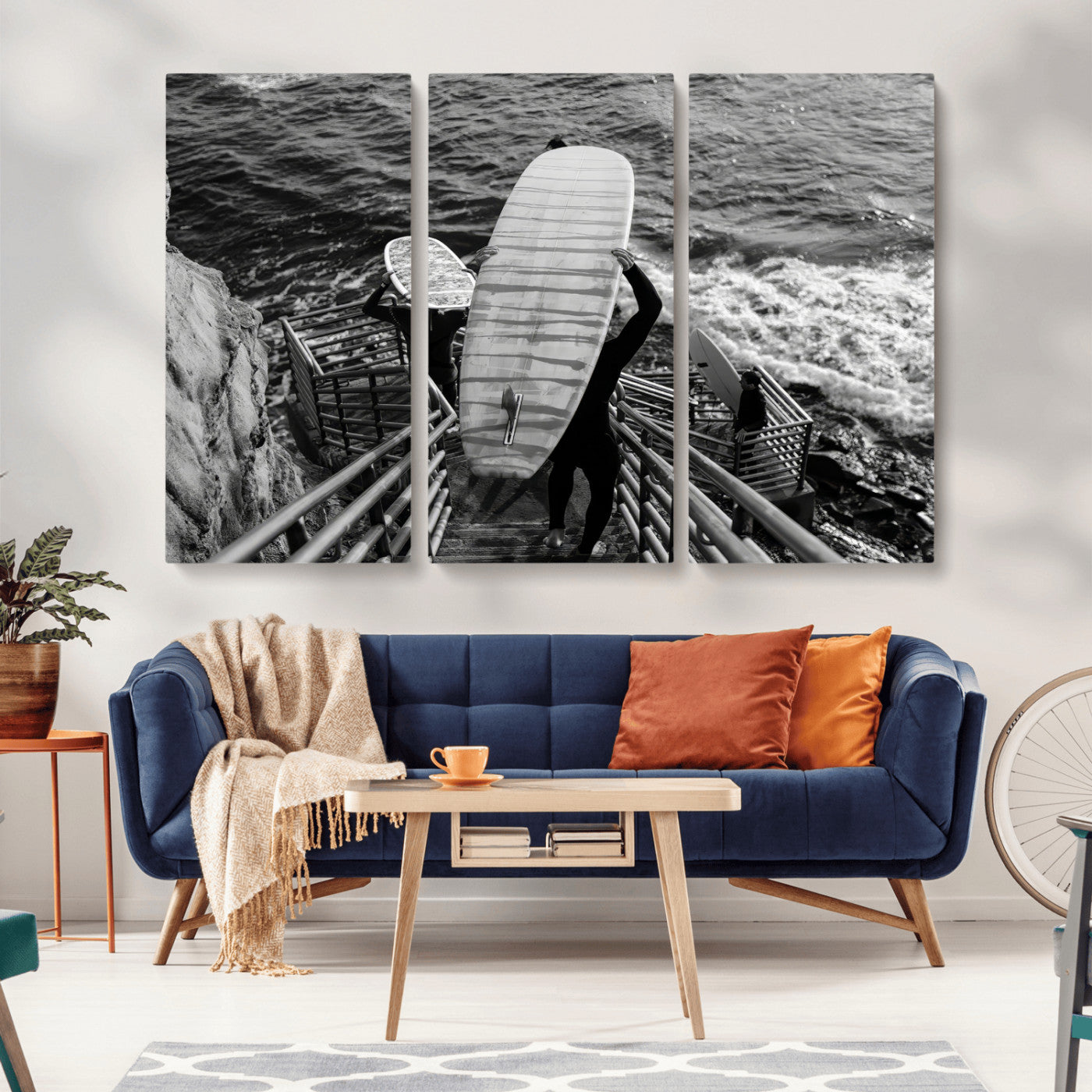 Black and white photo of surfers carrying boards down a rugged cliffside stairway, capturing a bold and adventurous coastal scene.