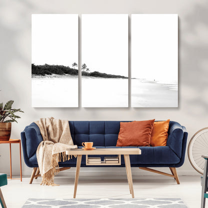A black and white minimalist coastal scene with a vast open beach, distant palm trees, and a lone figure walking along the shoreline, evoking serenity and solitude.