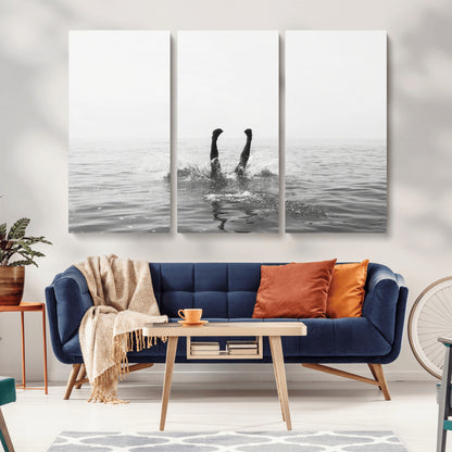 A black and white minimalist water scene capturing a playful splash as a swimmer dives upside down, creating a carefree and artistic aquatic aesthetic.
