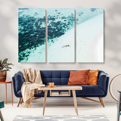 Canvas featuring an aerial view of a swimmer in shallow turquoise waters with coral patterns, ideal for tropical coastal home decor.
