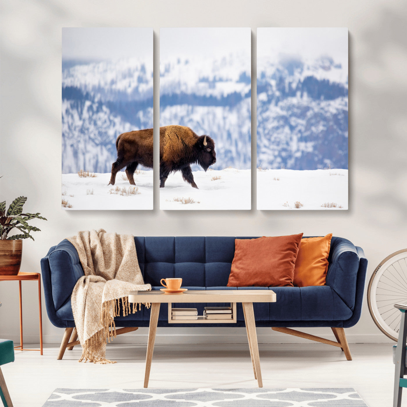 A lone bison walks across snowy ground with blue-toned mountain range behind, ideal for rustic or western farmhouse interiors.