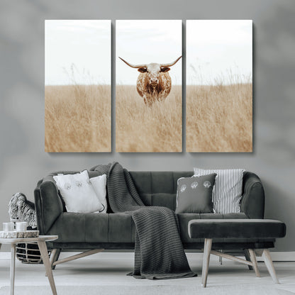 Texas Longhorn bull standing alone in dry grass with neutral tones, ideal for rustic western or cowboy-themed wall decor.
