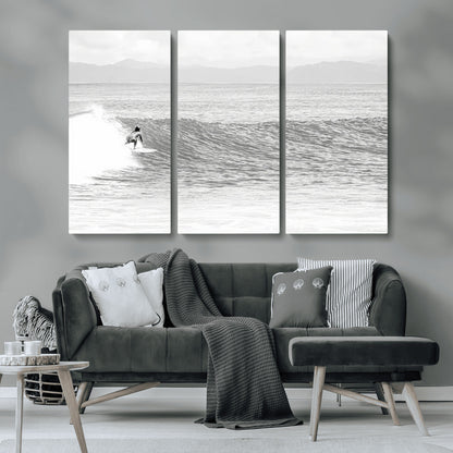 Monochrome photo of a surfer riding a wave with distant mountains, ideal for coastal motion or black and white surf-themed wall decor.