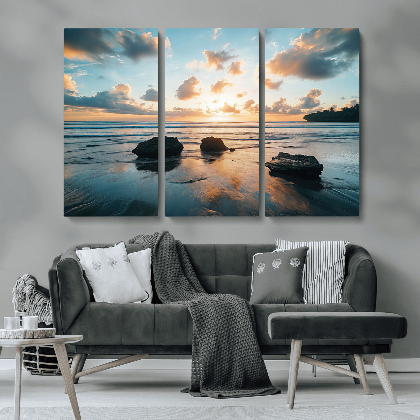 A serene beach at sunset with vibrant clouds, calm water, and rocks in the foreground reflecting the warm colors of the setting sun.