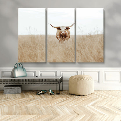 Texas Longhorn bull standing alone in dry grass with neutral tones, ideal for rustic western or cowboy-themed wall decor.