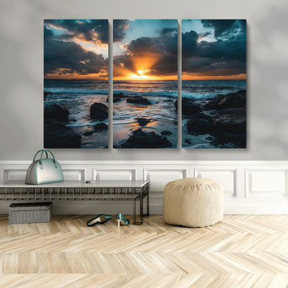 An awe-inspiring sunset over the ocean with rays of light piercing through dramatic clouds, creating a beautiful seascape with rocks in the foreground.