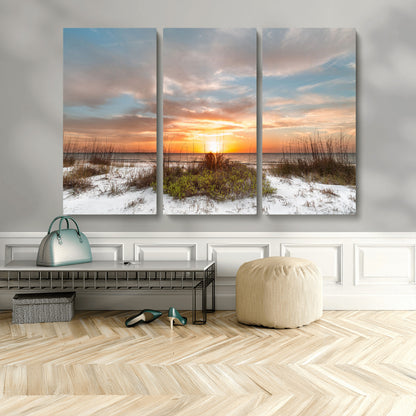 A tranquil beach scene featuring golden sunset hues over the water, with grasses in the foreground and a peaceful, serene atmosphere.