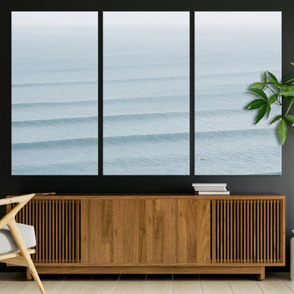 Framed canvas of repeating ocean waves with a distant solo surfer, ideal for minimalist ocean or calm coastal wall decor.