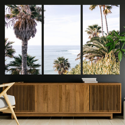 Scenic coastal view with tall palm trees overlooking a calm ocean, soft blue waves, and surfers in the distance, creating a peaceful tropical vibe.