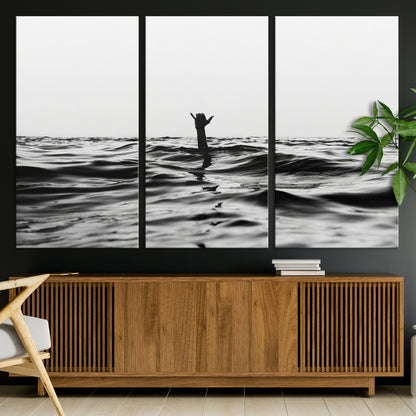Black and white ocean with a hand making a surfer sign among dark waves, creating a dramatic and minimalist seascape with bold contrast.