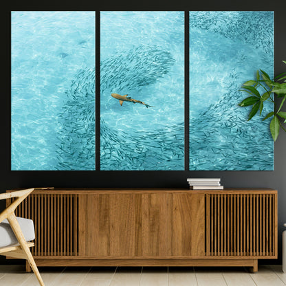Aerial view of a shark swimming through a swirl of fish in clear turquoise waters, perfect for calm coastal or beach house decor.