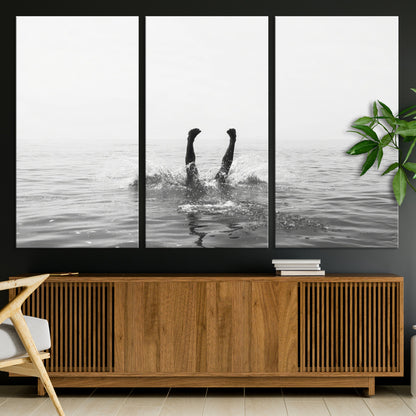 A black and white minimalist water scene capturing a playful splash as a swimmer dives upside down, creating a carefree and artistic aquatic aesthetic.
