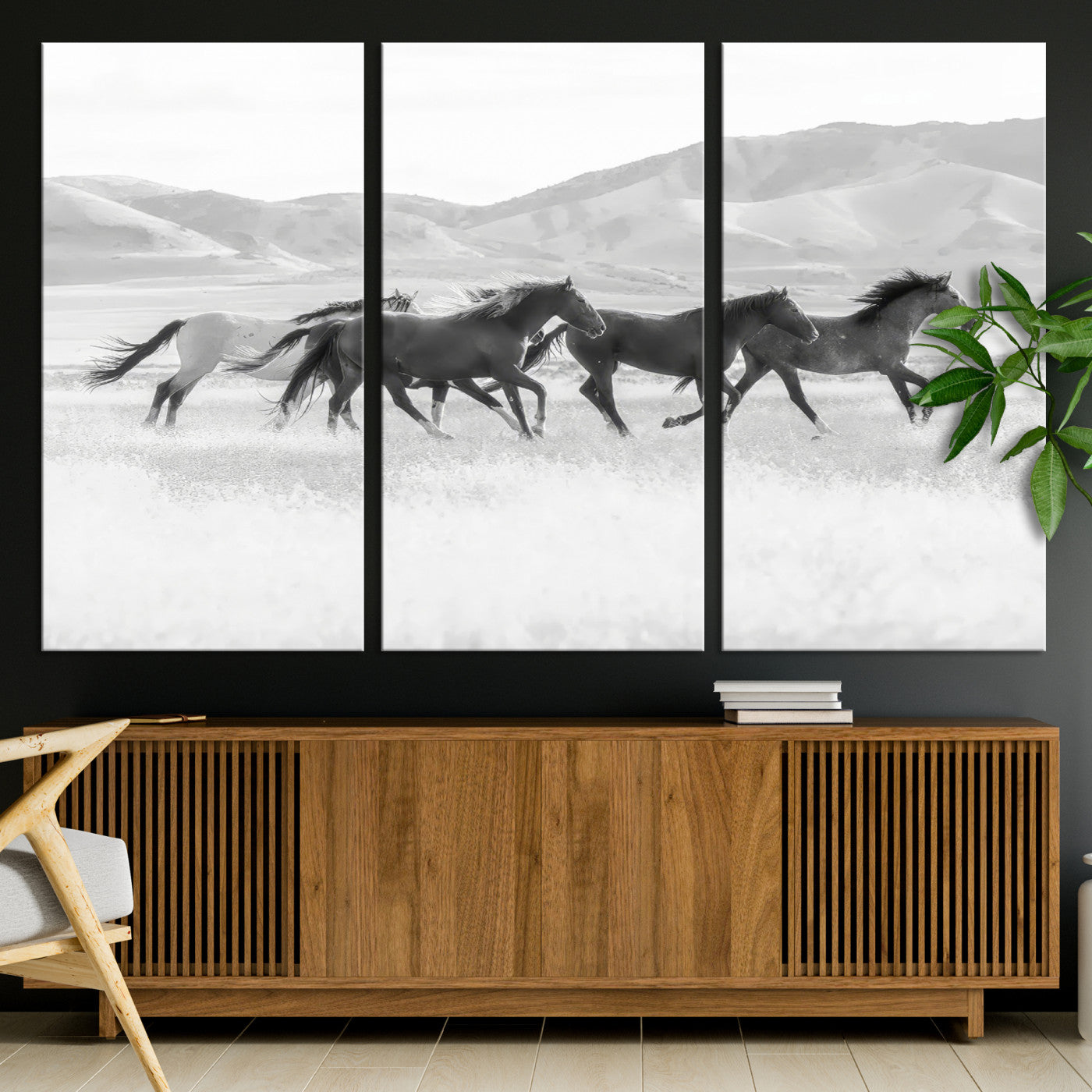 A black and white image of wild horses running freely across an open grassland, capturing the power and beauty of untamed nature in a rustic western setting.