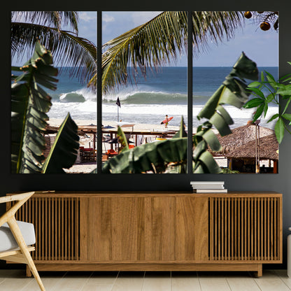 Canvas wall art of a tropical surf scene framed by palm trees, with a surfer on the shore and waves rolling in, ideal for beach-themed decor.