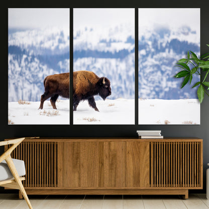 A lone bison walks across snowy ground with blue-toned mountain range behind, ideal for rustic or western farmhouse interiors.