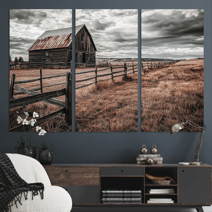 Framed canvas of a rustic barn under a moody sky with weathered fence and dark fields, ideal for farmhouse or rural-style wall decor.