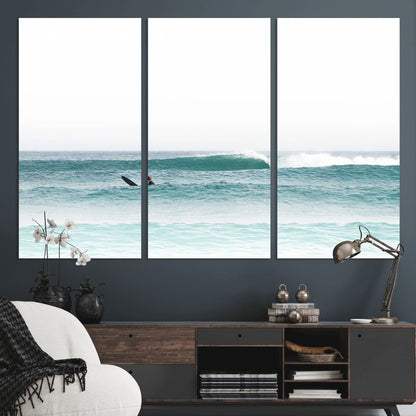 Minimalist photo of a lone surfer on calm aqua waves under bright sky, perfect for Scandinavian coastal or serene ocean-inspired home decor.