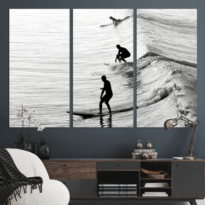 Black and white photo of surfers riding waves in a moody, high-contrast scene, ideal for modern coastal or surf-inspired home decor.