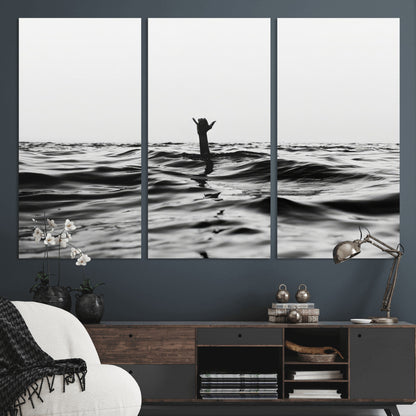 Black and white ocean with a hand making a surfer sign among dark waves, creating a dramatic and minimalist seascape with bold contrast.