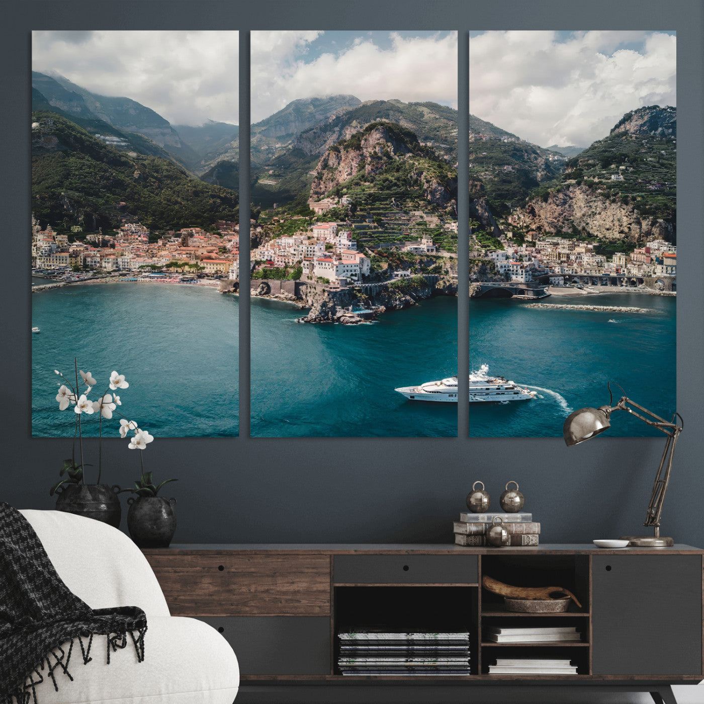Aerial view of Amalfi Coast, Italy, with colorful hillside houses, lush green mountains, and a luxury yacht sailing in turquoise waters.