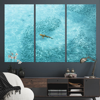 Aerial view of a shark swimming through a swirl of fish in clear turquoise waters, perfect for calm coastal or beach house decor.