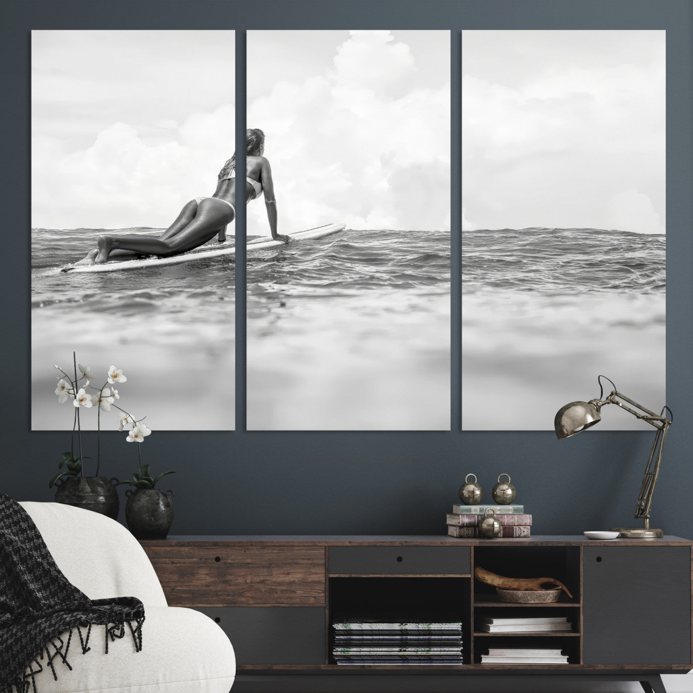 A black and white ocean scene featuring a surfer girl waiting on her board, gazing at the horizon, capturing a tranquil and adventurous coastal moment.