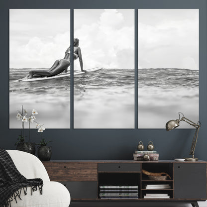 A black and white ocean scene featuring a surfer girl waiting on her board, gazing at the horizon, capturing a tranquil and adventurous coastal moment.