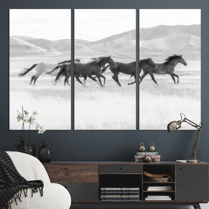 A black and white image of wild horses running freely across an open grassland, capturing the power and beauty of untamed nature in a rustic western setting.